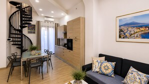 A modern living space with a spiral staircase, a dining area, a sofa with patterned cushions, and a cityscape painting. - Bedda Sicily (Riposto)
