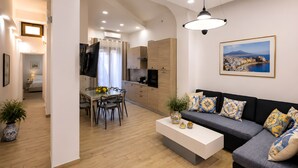 A modern living room with a sofa, coffee table, and a dining area with chairs and a table. - Bedda Sicily (Riposto)