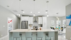 A modern kitchen with a large island, stainless steel appliances, and pendant lighting.
