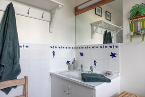 A bathroom with a white sink, mirror, and blue decorative tiles. - Juniper House -  a house that sleeps 17 guests  in 8 bedrooms (Kingsbridge)