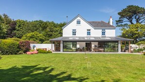 A large, white house with a spacious front yard and a covered patio area. - Juniper House -  a house that sleeps 17 guests  in 8 bedrooms (Kingsbridge)