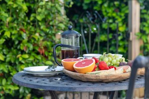 A round metal table with a fruit platter, a coffee pot, and a teapot. - Juniper House -  a house that sleeps 17 guests  in 8 bedrooms (Kingsbridge)