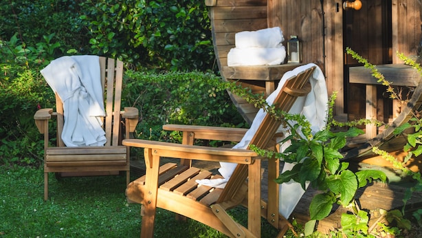 Two wooden chairs with white towels, a wooden bench, and a rustic wooden structure with a door and a light fixture. - Juniper House -  a house that sleeps 17 guests  in 8 bedrooms (Kingsbridge)