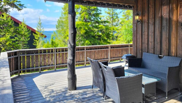A covered outdoor deck with wicker furniture and a grill. - 2 bedroom nice home in Hafjell (Hafjell)