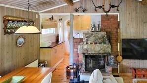 A cozy living room with a stone fireplace, wooden furniture, and a television mounted on the wall. - 2 bedroom nice home in Hafjell (Hafjell)