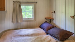 A bedroom with a bed, a window with a curtain, a small table, and a wall-mounted light fixture. - 2 bedroom nice home in Hafjell (Hafjell)
