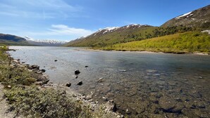 Un río transparente con orillas rocosas y montañas al fondo.