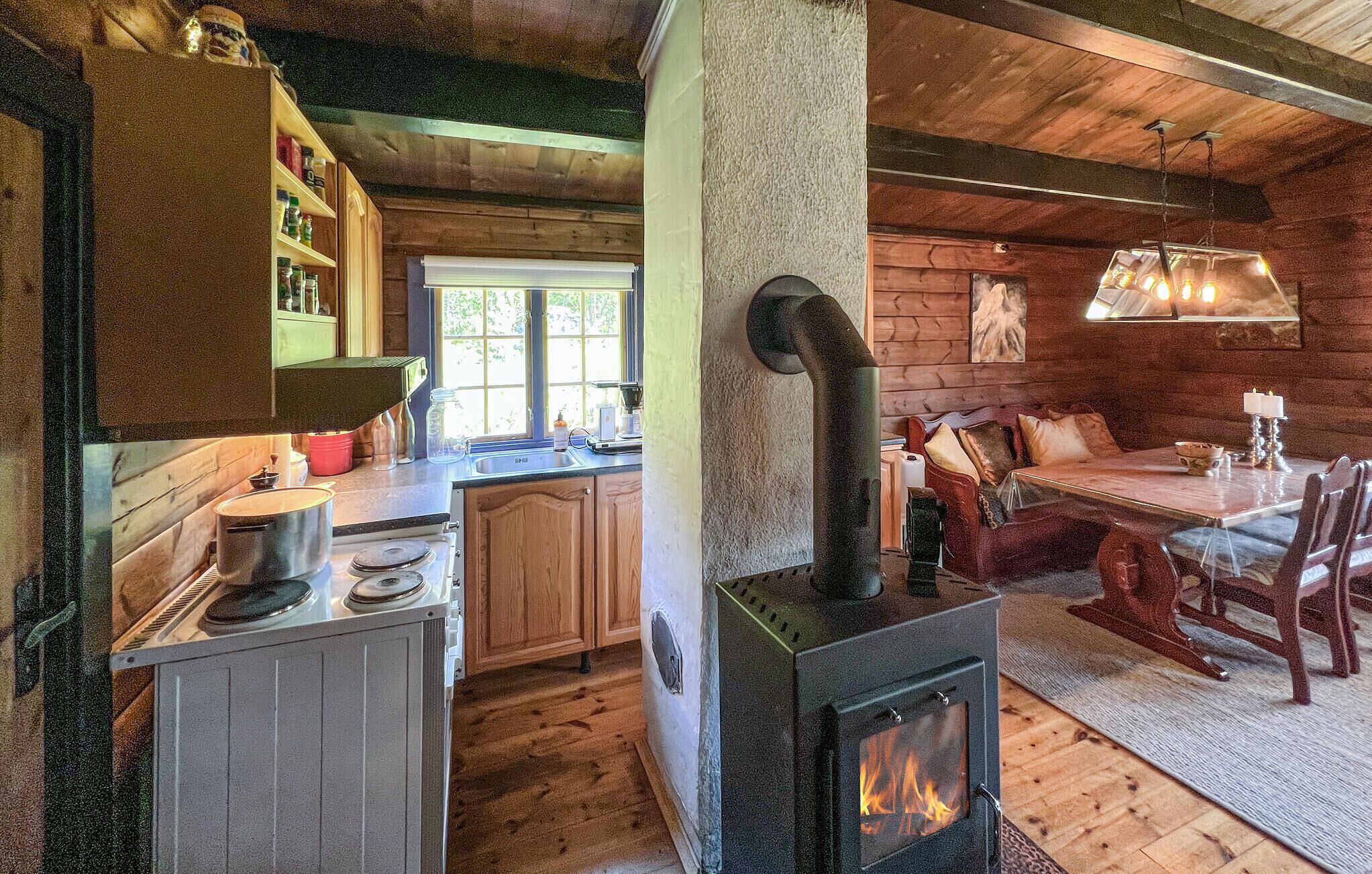 Een gezellig interieur van een chalet, met een keuken, eethoek en een houtkachel.