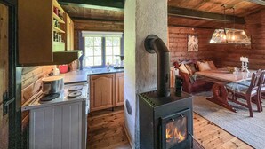 Acogedor interior de cabaña con cocina, comedor y estufa de leña.