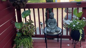 A wooden deck with a Buddha statue, potted plants, and a hanging light fixture.