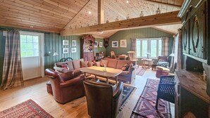 Ein gemütliches, rustikales Wohnzimmer mit Holzboden, einer großen Couch, einem Couchtisch und einem Kamin.
