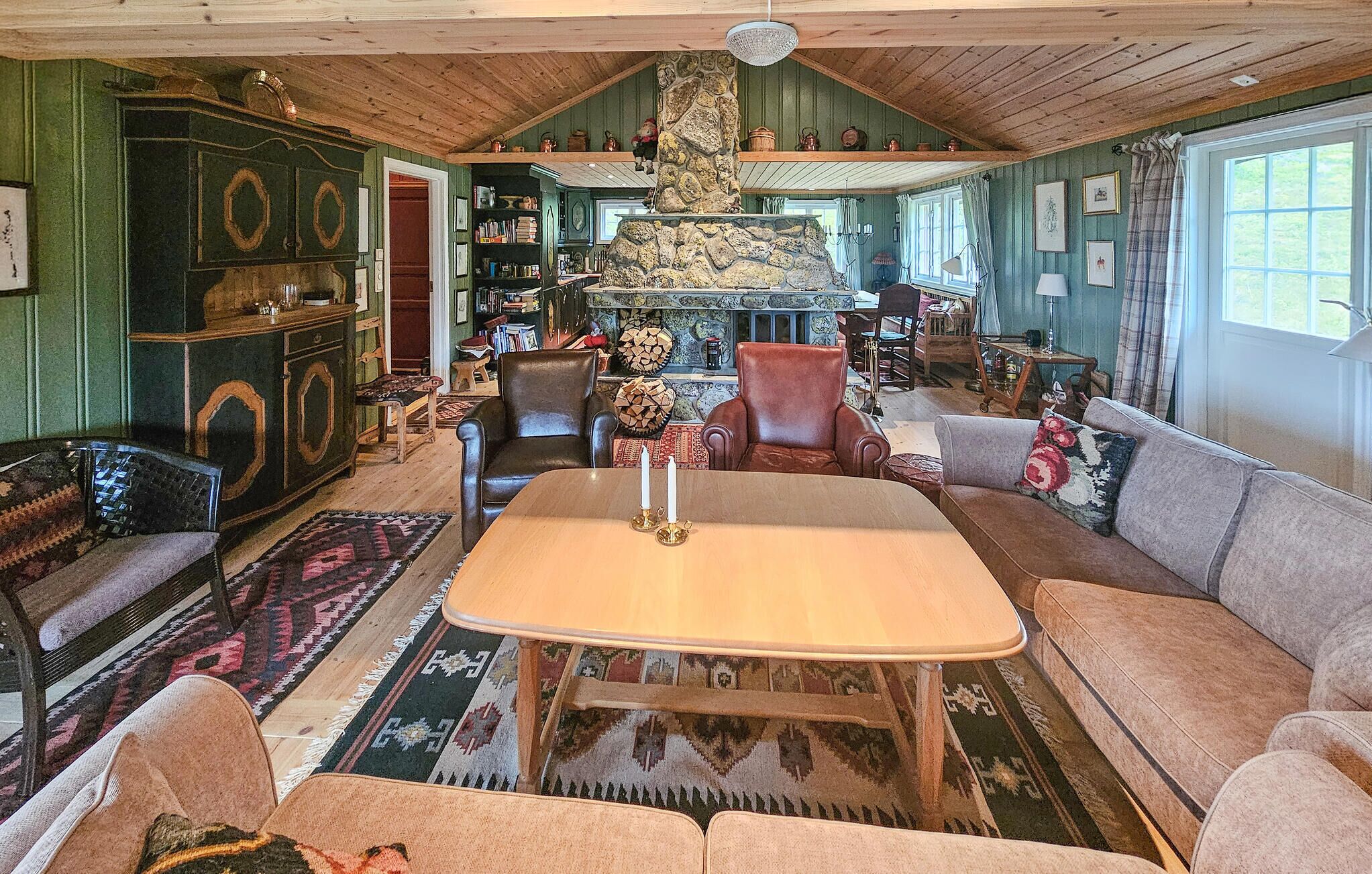 A cozy living room with a stone fireplace, wooden furniture, and a variety of decorative items.