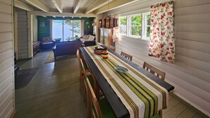 A dining area with a long table, chairs, and a bench. There is a window with floral curtains and a view of greenery outside. - Amazing home in Svelvik with WiFi (Svelvik)