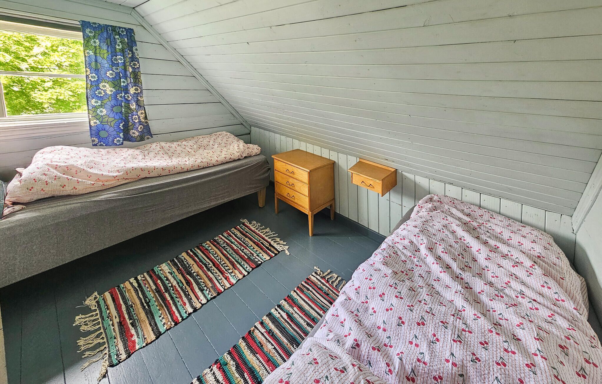 Une petite chambre mansardée, chaleureuse et accueillante, avec un lit superposé, une commode en bois et une petite table de chevet.
