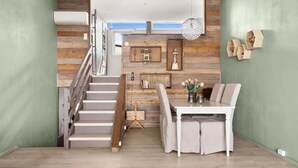 A modern interior with a staircase, a dining area with a table and chairs, and wooden wall paneling.