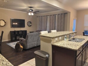 A modern living room with a TV, seating, and a ceiling fan. - The Hamilton Hideaway (Lewisville)