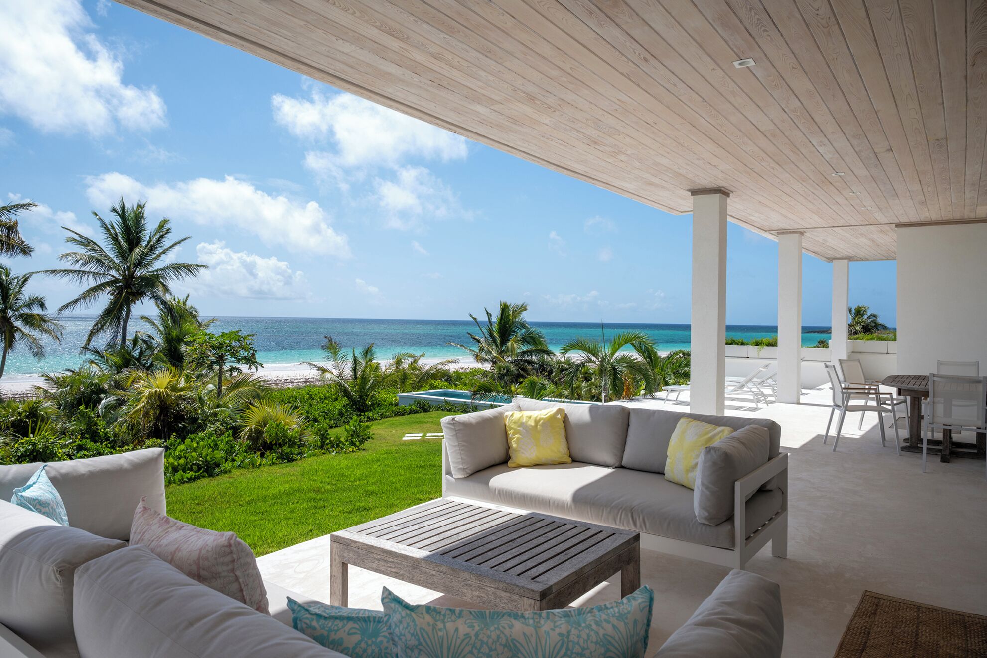 A covered outdoor seating area with a view of the beach and ocean.