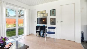 A modern living room with a large window, a flat-screen TV, a bookshelf, and a blue chair. - Awesome home in Nørre Nebel with WiFi (Nørre Nebel)