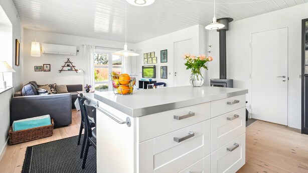 A modern kitchen with white cabinetry, a central island, pendant lighting, and a view of the living area. - Awesome home in Nørre Nebel with WiFi (Nørre Nebel)