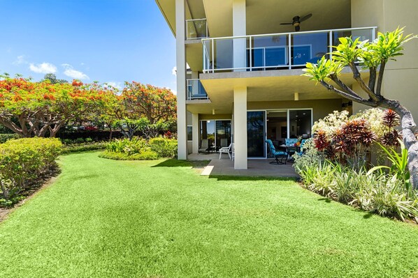 A modern building with a well-maintained lawn, outdoor seating area, and a variety of plants.