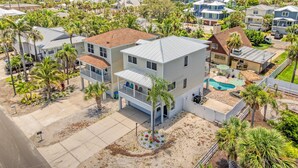 A two-story house with a balcony, a swimming pool, and a well-maintained lawn. - Dolphin Resort | Private Pool, Spa, Tiki Bar, Game Room & 3 Min Walk to Beach (Holmes Beach)