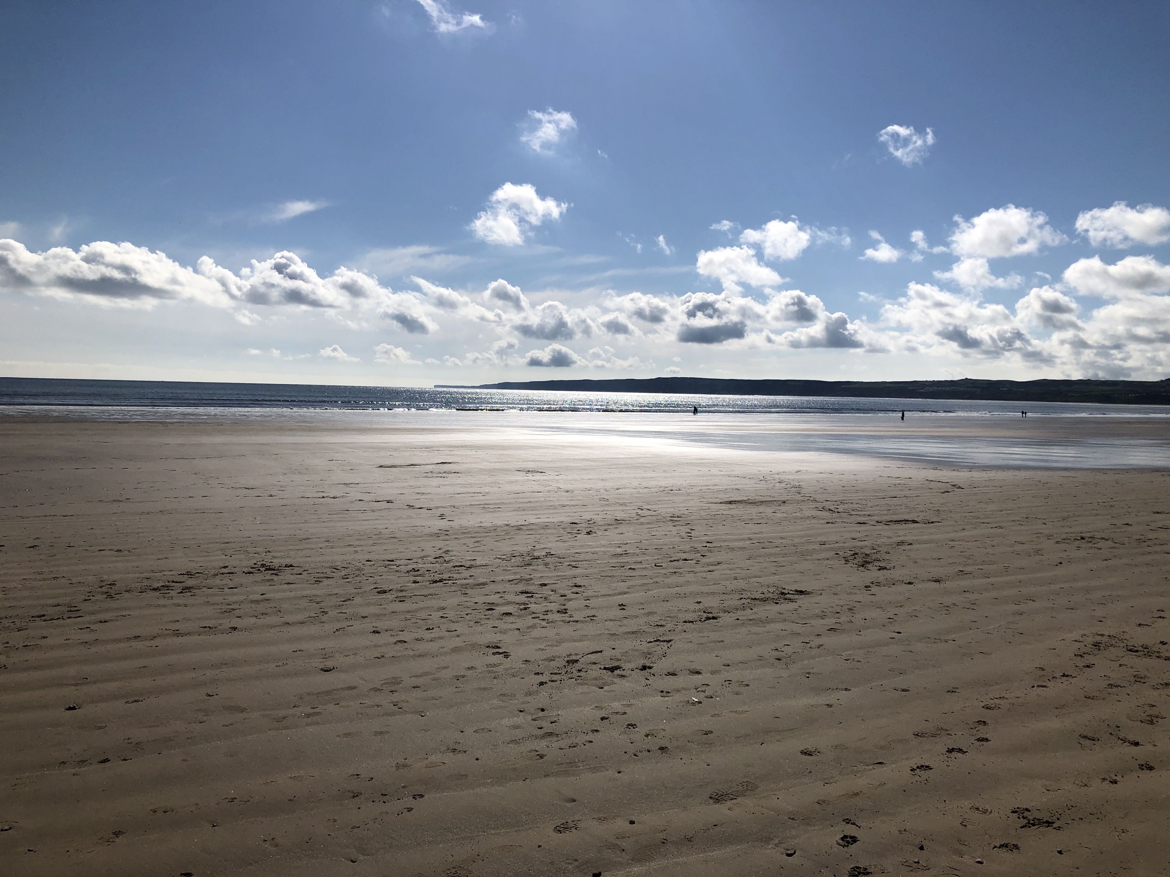 A wide beach with footprints and a clear sky.