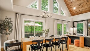 Un coin repas avec une table en bois, des chaises noires et un lustre.
