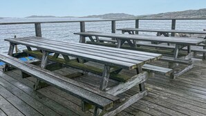 A wooden pier with picnic tables extending over a body of water, with mountains in the background. - 1 bedroom cozy home in Vrångö (Vrångö)