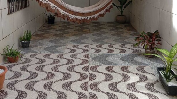 Un hamac dans un patio carrelé, agrémenté de plantes en pot.