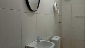 Une salle de bain avec un lavabo blanc, des toilettes et un miroir.