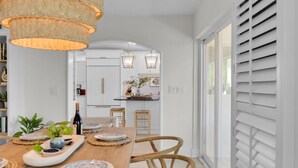 A dining area with a wooden table, woven placemats, and wicker chairs. - Reel Joy | Florida Keys Waterfront Home + Pool & Private Dock (Marathon)