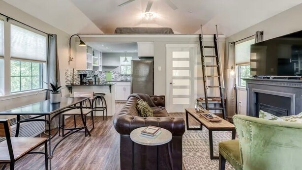 A spacious living room with a leather couch, a dining table, and a fireplace.