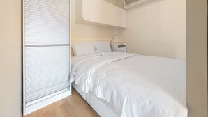 A bedroom with a bed, bedside table, and a wardrobe. - Mosiężna Przystań Homely Apartment (Wrocław)