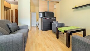 A modern living room with a sofa, armchair, and a small table. There is a sliding door leading to a bathroom. - Mosiężna Przystań Homely Apartment (Wrocław)