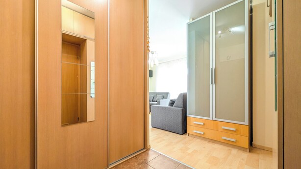 A modern room with a wooden wardrobe, a grey sofa, and a large sliding door closet. - Mosiężna Przystań Homely Apartment (Wrocław)