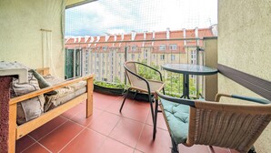 A balcony with a wooden bench, wicker chairs, and a small table. - Mosiężna Przystań Homely Apartment (Wrocław)