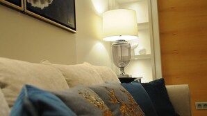 Una habitación de hotel con un sofá color beige, una lámpara y un cuadro en la pared.