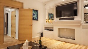 Una sala de estar moderna con chimenea, un televisor de pantalla plana grande y una puerta de madera.