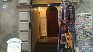 Una fachada con un letrero que dice 'Turkus' joyería, una escalera que lleva a una puerta y una exhibición de postales.