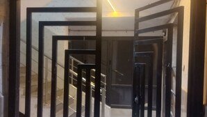 A modern interior with a geometric metal gate, a staircase, and a bright light fixture.