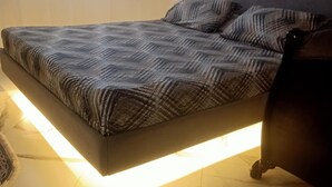A modern bedroom with a bed, a nightstand, and a lamp.