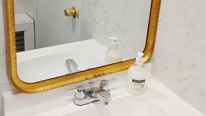 A bathroom with a white sink, a gold-framed mirror, and a bottle of spa soap. - The Williams Center (New London)