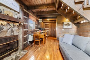 L’intérieur d’un chalet rustique, avec une cheminée en pierre, une table à manger en bois et un canapé.