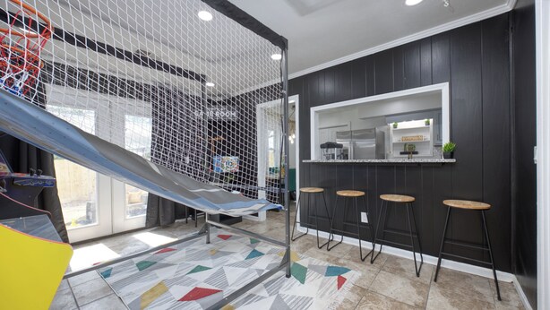 A modern kitchen with a black backsplash, a kitchen island, and a bar area with stools. - Military in Style/Movie Room /Game Room Minutes from Ft. Benning & Downtown area (Columbus)
