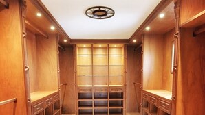 Un grand dressing avec des étagères et des tiroirs en bois, un sol carrelé et un luminaire au plafond.