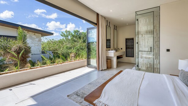A modern bedroom with a large bed, a glass shower, and a view of greenery. -  Bōld - Modern Tropical Pool Villas (Pecatu)