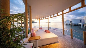 Un salon de bord de mer avec un canapé, des tables et une vue sur l’eau.