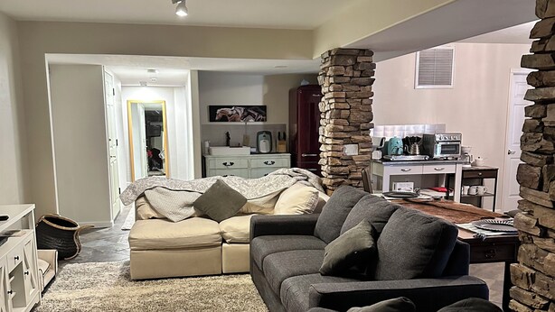 A living room with a sectional sofa, a coffee table, and a stone accent wall. - 3-bedroom apartment in charming Prescott Valley with WiFi, AC, and Heat (Prescott Valley)