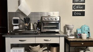 A compact kitchen with a built-in oven, a coffee maker, and a hanging sign listing sugar, steria, hot chocolate, coffee, and tea. - 3-bedroom apartment in charming Prescott Valley with WiFi, AC, and Heat (Prescott Valley)