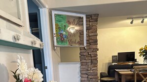 A living room with a stone accent wall, a white door, a TV, a dining area, and a white vase with flowers. - 3-bedroom apartment in charming Prescott Valley with WiFi, AC, and Heat (Prescott Valley)